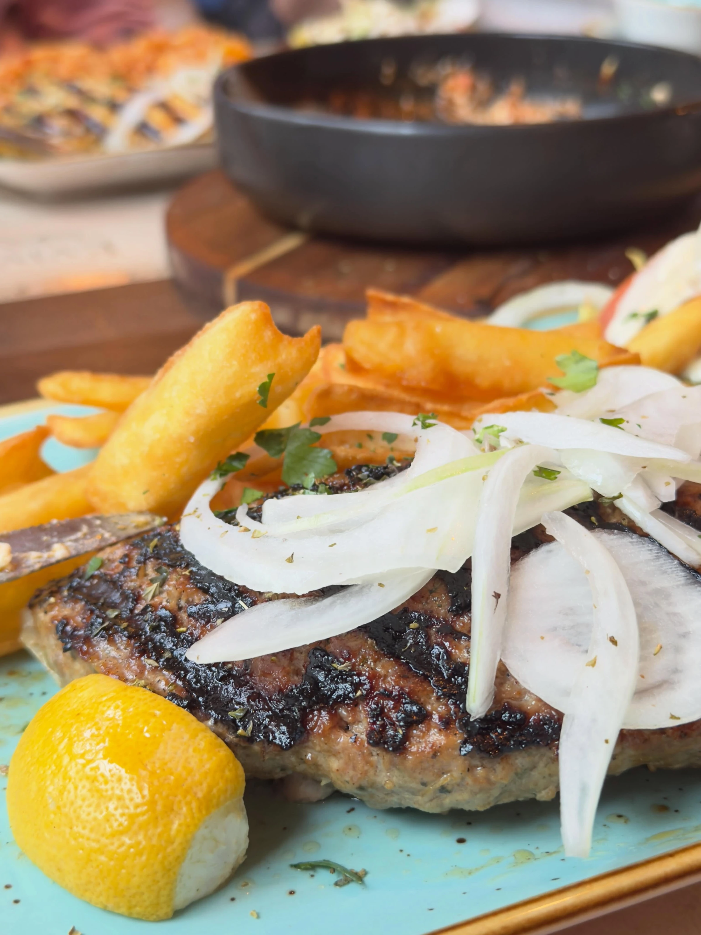 Griechisches Grillgericht mit Zwiebeln, Pommes und Zitrone